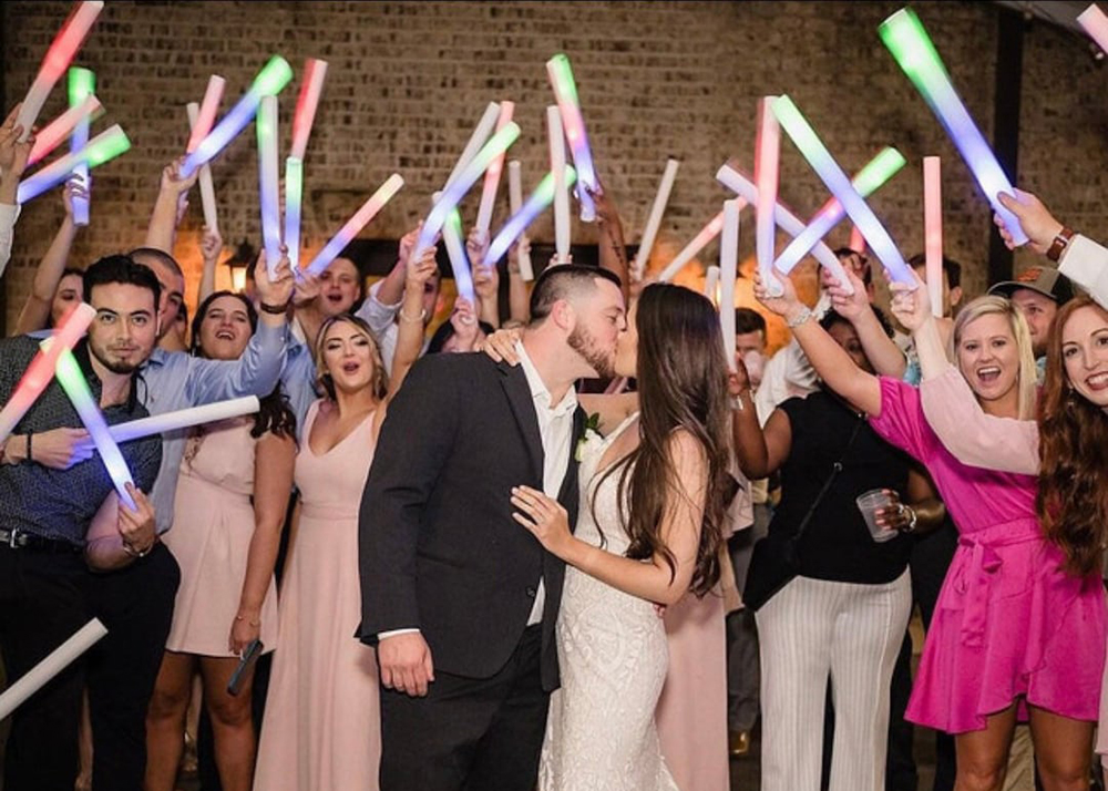 Wedding guests celebrating on the dance floor with neon glow sticks and professional DJ entertainment
