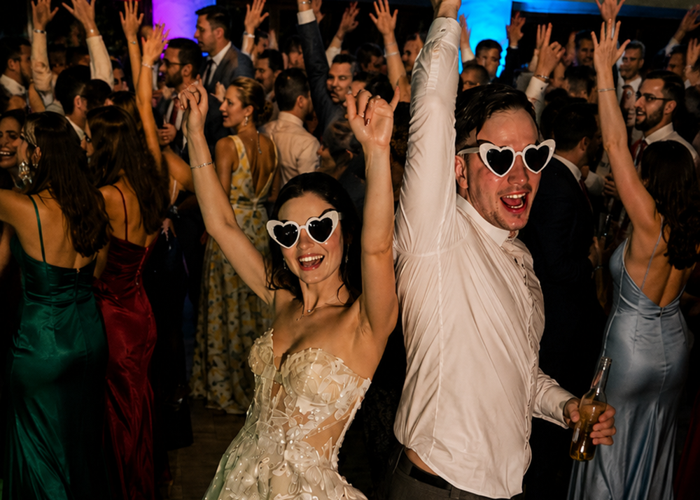Wedding guests celebrating on the dance floor with neon glow sticks and professional DJ entertainment